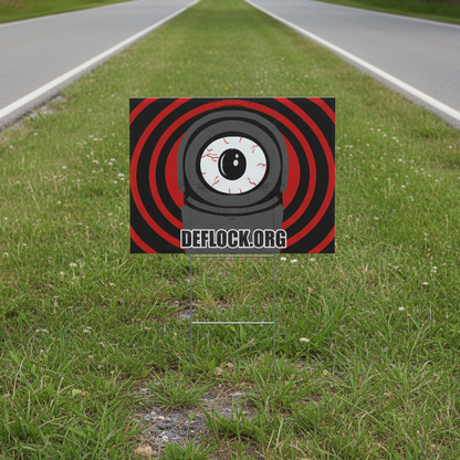 A yard sign featuring a stylized eye graphic with red concentric rings on a black background, with the text 'DEFLOCK.ORG' across the middle and a white metal stake below.